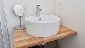 Un baño con un lavamanos blanco, un espejo redondo y una encimera de madera.