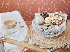Une table à manger agrémentée d’un centre de table en fibres tressées, de verres transparents, d’un bol et d’une cuillère.