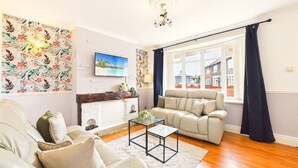 Ein Wohnzimmer mit einer Couch, einem Couchtisch, einem Kamin und einem großen Fenster mit Vorhängen.
