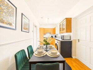 A compact kitchen with wooden cabinets, a microwave, and a sink. - Matford House | Spacious Stay | Sleeps 6 | Parking (Middlesbrough)