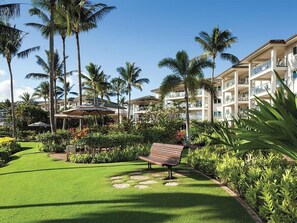 Ein Resort mit gepflegter Rasenfläche, Palmen und einem Gebäude mit mehreren Balkonen.