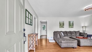 Una sala de estar moderna con un sofá modular, piso de madera y vistas al exterior.