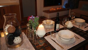 A dining table set with plates, glasses, and a candle, with a vase of flowers and a bottle of wine on the table. - Sweet Tabaiba Suite - casita con vistas al mar, terraza privada y Wi-Fi (La Asomada)