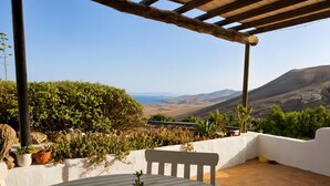 A patio with a table and chairs, surrounded by potted plants and a view of a mountainous landscape. - Sweet Tabaiba Suite - casita con vistas al mar, terraza privada y Wi-Fi (La Asomada)