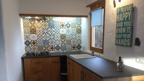 A kitchen with a tiled backsplash, wooden cabinets, a sink, and a mirror. - Sweet Tabaiba Suite - casita con vistas al mar, terraza privada y Wi-Fi (La Asomada)