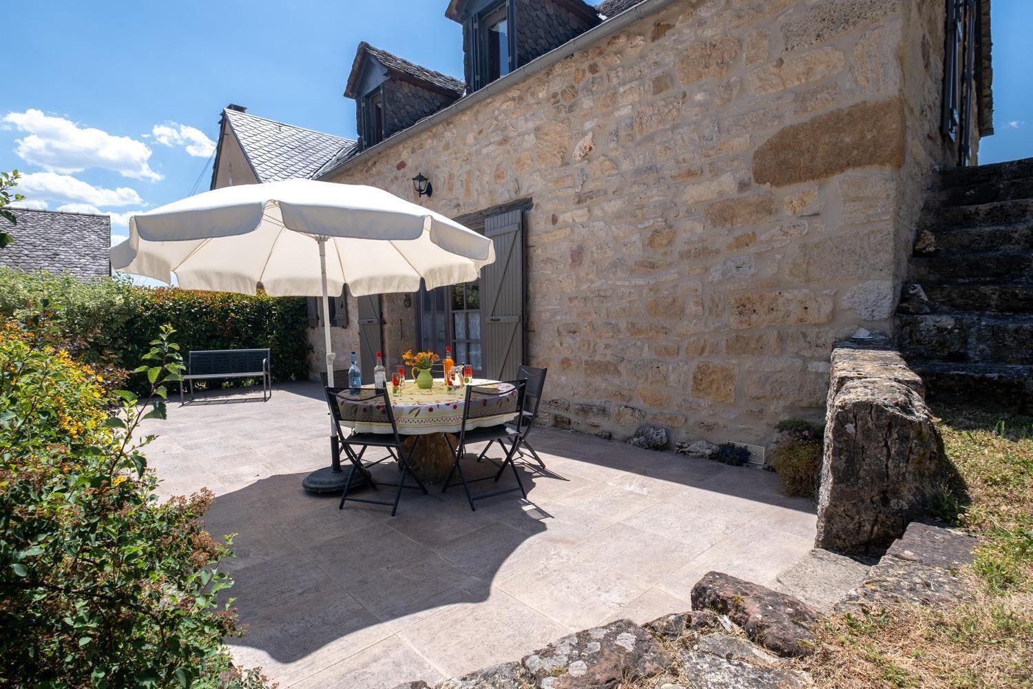 An outdoor patio with a round table, chairs, and a large umbrella.