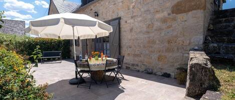 An outdoor patio with a round table, chairs, and a large umbrella.