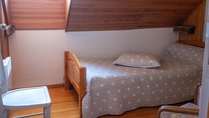 A small, single-bed room with a sloped ceiling, a wooden chair, and a window. - La Roque Vacation Rental - CANOURGUE (LA) (CANOURGUE (LA))