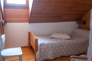 A small, single-bed room with a sloped ceiling, a wooden chair, and a window. - La Roque Vacation Rental - CANOURGUE (LA) (CANOURGUE (LA))