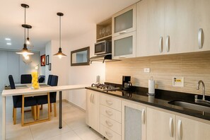 A modern kitchen with a central island, built-in microwave, and a dining area with chairs. - Envigado Comfortable Modern · Wifi 300 MB · Metro (Envigado)