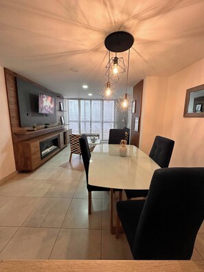 A modern dining area with a large table, black chairs, and pendant lights. - Envigado Comfortable Modern · Wifi 300 MB · Metro (Envigado)