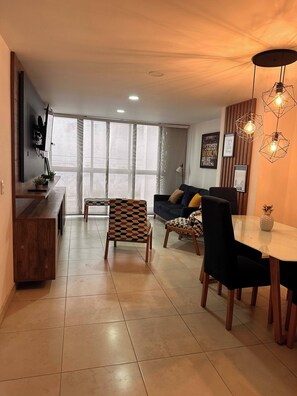 A modern living room with a sofa, chairs, a dining table, and a TV mounted on the wall. - Envigado Comfortable Modern · Wifi 300 MB · Metro (Envigado)