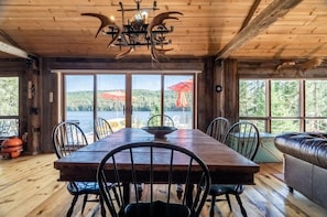 A wooden interior with a dining table, chairs, and a leather sofa.