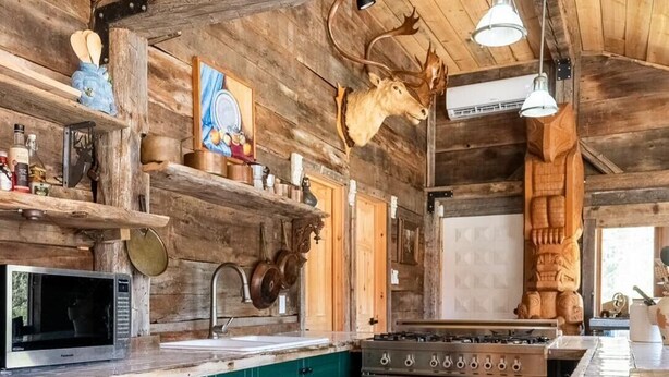 A rustic kitchen with wooden beams, a stove, and a sink. - Beautifully Private Chalet in Sainte Anne du Lac! Perfect lake! (Sainte Anne du Lac)
