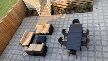 Une terrasse avec une table et des chaises, un canapé et un petit coin jardin.