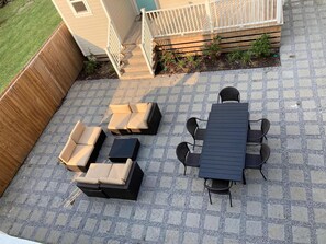 Une terrasse avec une table et des chaises, un canapé et un petit coin jardin.