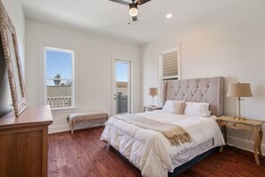 Une chambre avec un grand lit, un banc en bois, un bureau et un balcon.