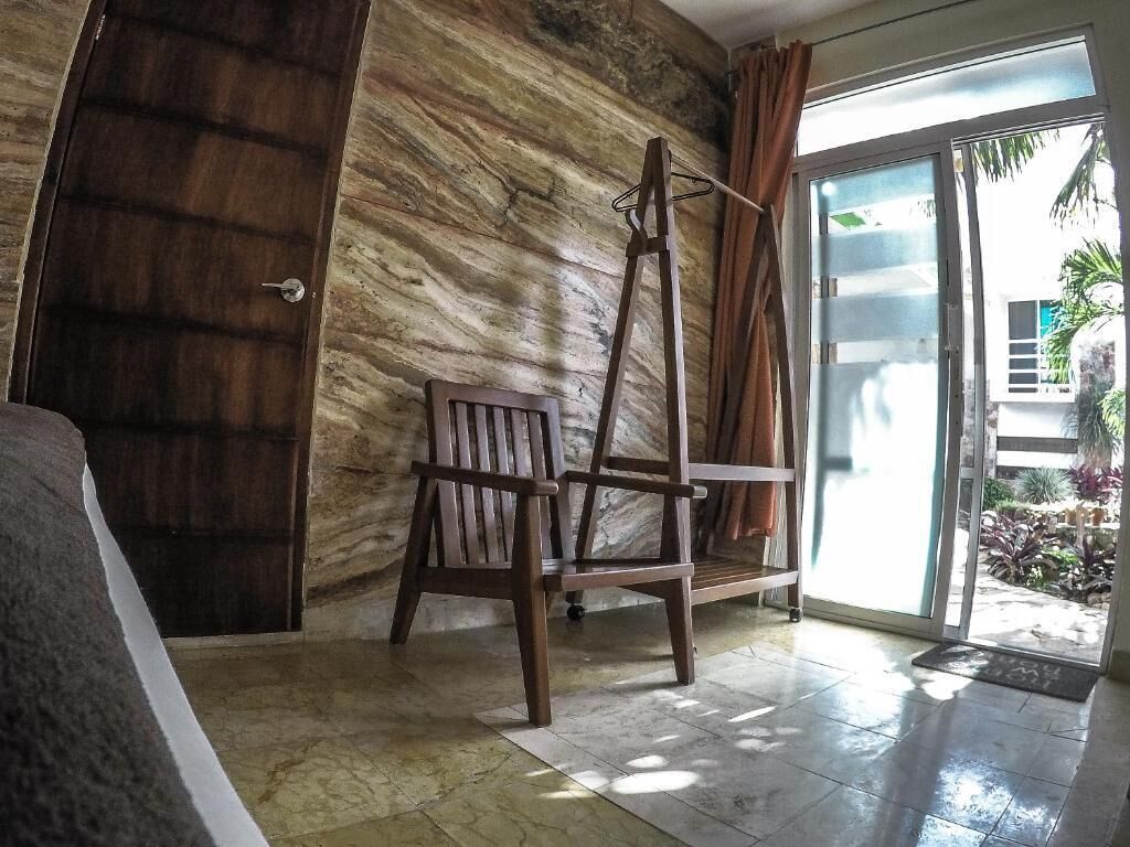 A room with a wooden chair, a door, and a view of the outside.