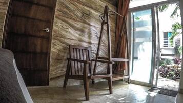 A room with a wooden chair, a door, and a view of the outside.