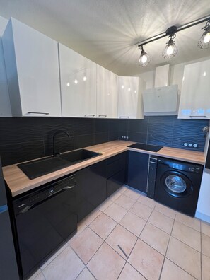 A modern kitchen with a dishwasher, washing machine, and a sink. - LE NID PROVENÇAL - Ground-floor apartment with garden, pool, and terrace (Le Pontet)