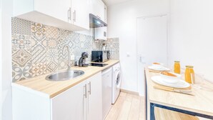 Et moderne køkken med hvide skabe, en stålvask, en mikrobølgeovn og en indbygget ovn.