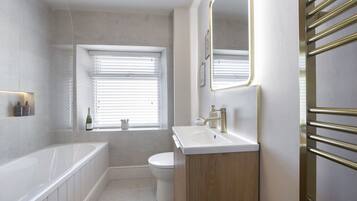 A modern bathroom with a bathtub, toilet, and sink.