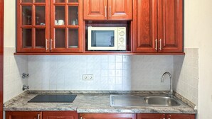 A kitchen with wooden cabinets, a microwave, a sink, and a granite countertop. - Stunning apartment in Pula with swimming pool (Pula)