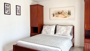 A bedroom with a bed, a wooden wardrobe, a nightstand, and a painting on the wall. - Stunning apartment in Pula with swimming pool (Pula)
