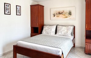 Ein Schlafzimmer mit einem Bett, einem Holzschrank, einem Nachttisch und einem Bild an der Wand.