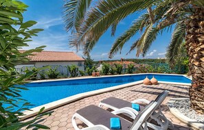 Ein Pool mit Liegestühlen, Palmen und einer gefliesten Terrasse.