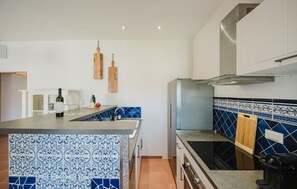 A modern kitchen with a central island, a built-in oven, and a backsplash with blue and white tiles. - Awesome home in Pula with house sea view (Pula)