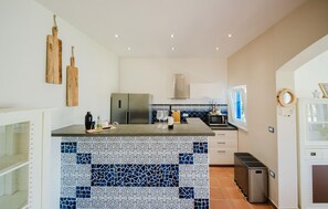 A modern kitchen with a central island, stainless steel appliances, and decorative tiles.