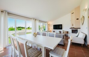 A spacious living area with a dining table, sofas, a TV, and a fireplace.