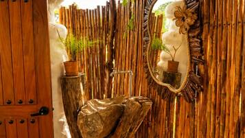 Una porta in legno, un lavandino in pietra, uno specchio e una parete di bambù.