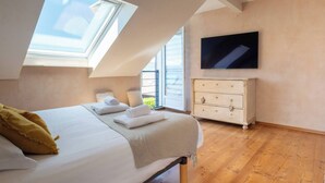 A bedroom with a bed, a dresser, a TV, and a skylight. - House Flaura - Lake View - Veyrier - 3 bedrooms (Veyrier-du-Lac)
