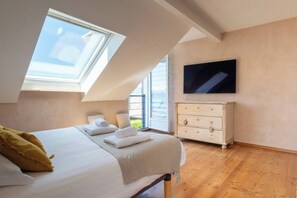 A bedroom with a bed, a dresser, a TV, and a skylight. - House Flaura - Lake View - Veyrier - 3 bedrooms (Veyrier-du-Lac)