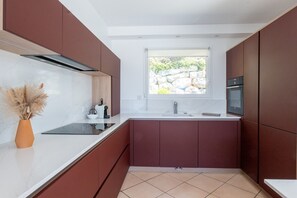 Une cuisine moderne avec une fenêtre, un four encastré et un plan de travail blanc.