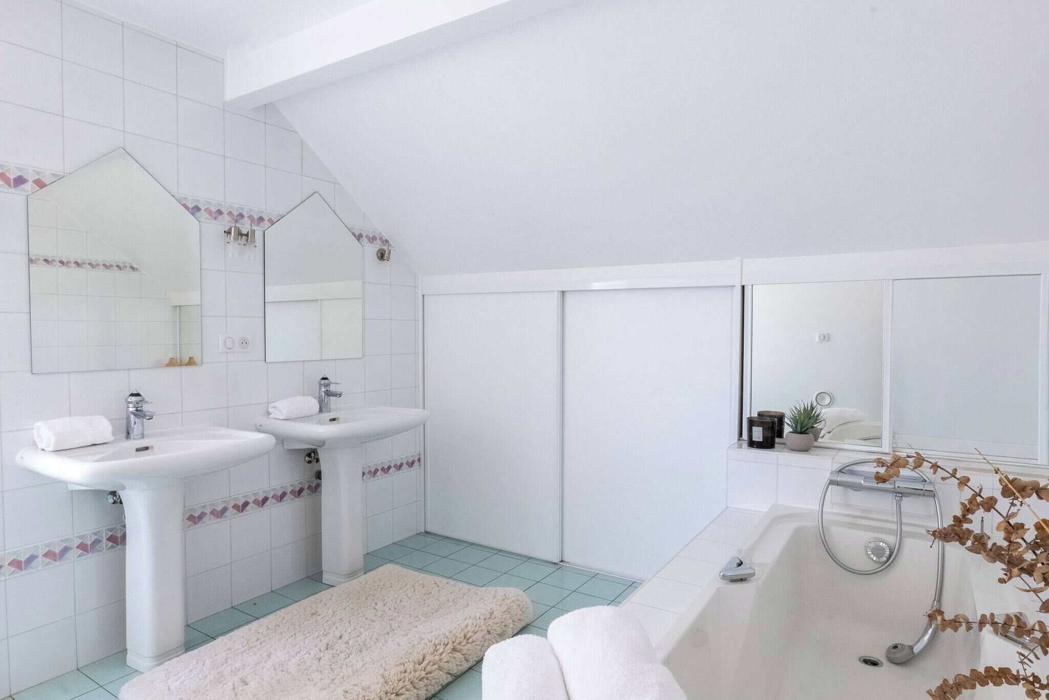 A modern bathroom with two sinks, a large mirror, and a bathtub.