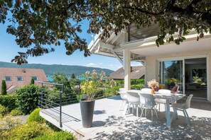 Eine Terrasse mit Tisch und Stühlen, einem Blumentopf und Blick auf die Berge.