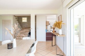 A modern kitchen with a wooden countertop, a dining table with chairs, and a staircase leading to another level. - House Flaura - Lake View - Veyrier - 3 bedrooms (Veyrier-du-Lac)