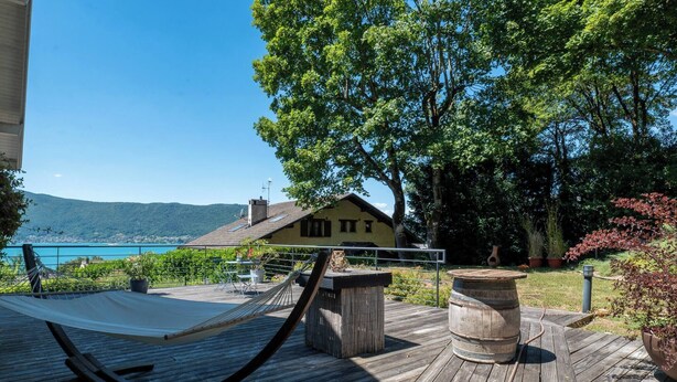 A wooden deck with a hammock, a barrel, and a view of a house and mountains. - House Flaura - Lake View - Veyrier - 3 bedrooms (Veyrier-du-Lac)