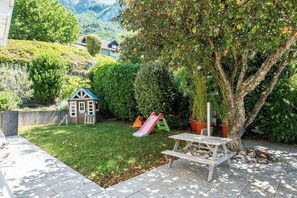 Un jardin avec une cabane, un toboggan et une table de pique-nique.