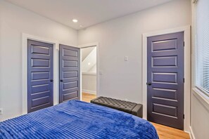 A bedroom with a bed, two doors, a bench, and a staircase. - 14 Room, 27 bed, Multi-Townhome Complex, Roof Decks, 2mi to DT! (Nashville)