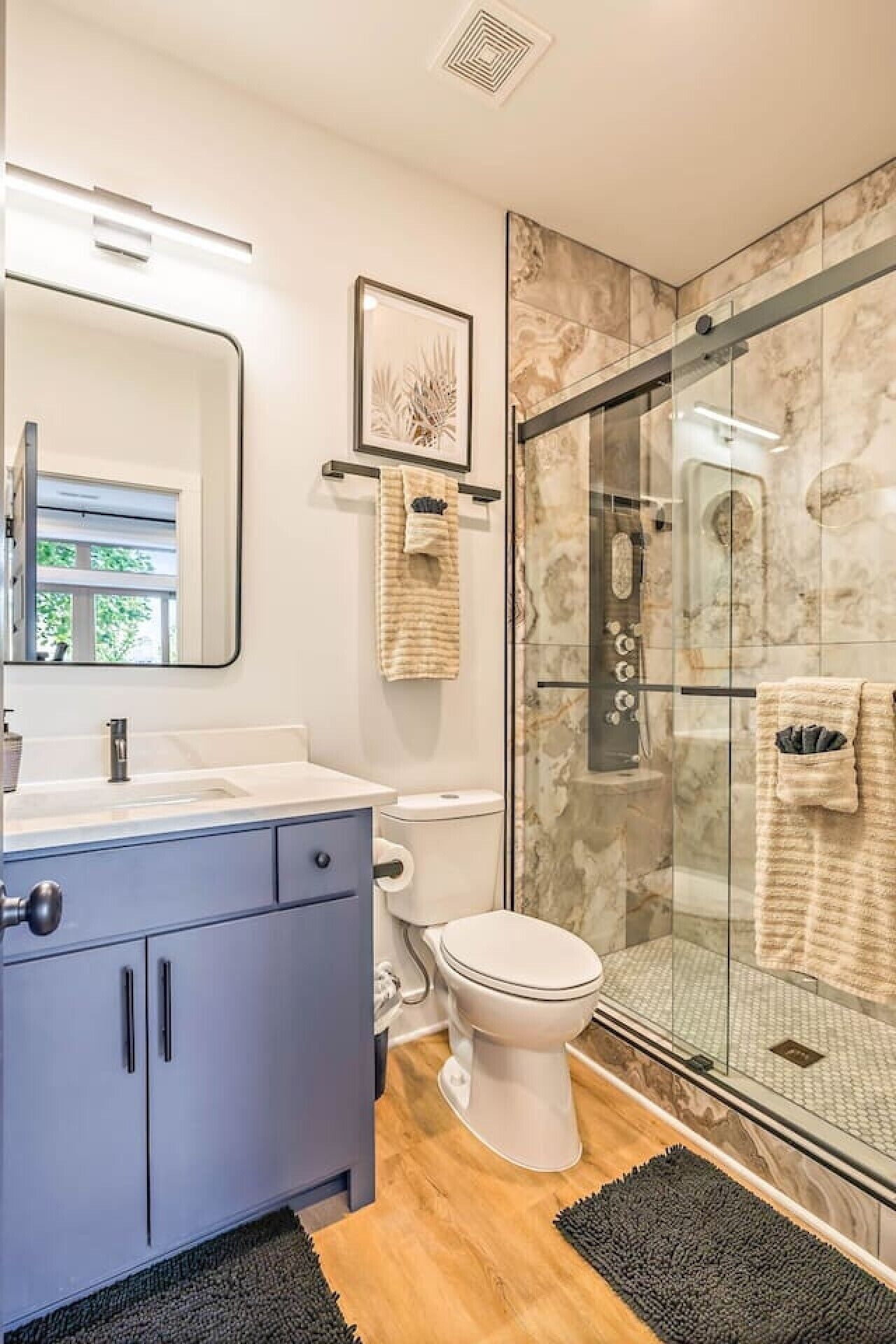 Een moderne badkamer met een douchecabine van glas, een wit toilet en een wastafel met spiegel.