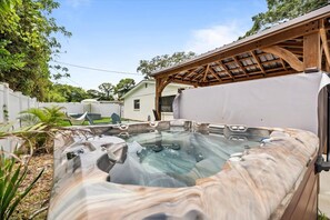 A hot tub with a wooden pergola overhead, surrounded by greenery and a white fence. - Walk to Park|Family Oasis w/ Stock Tank Pool & Spa (Largo)