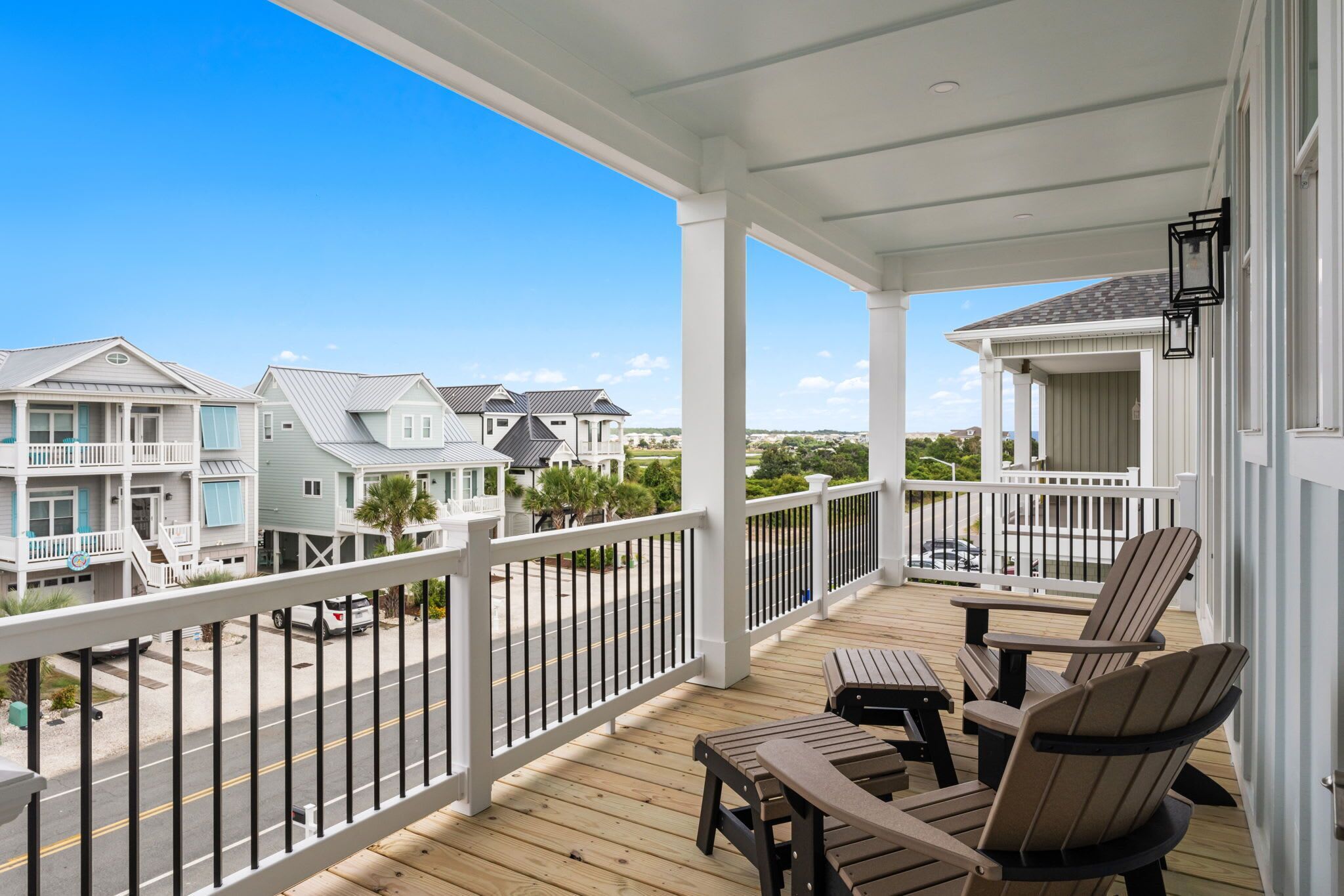 A wooden deck with outdoor furniture, a white railing, and a view of neighboring houses.