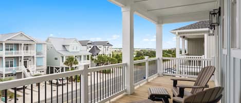 A wooden deck with outdoor furniture, a white railing, and a view of neighboring houses.