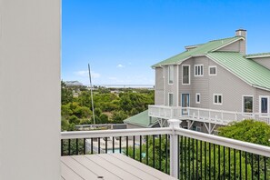 Ein zweistöckiges Haus mit einem grünen Dach und einem weißen Balkon.