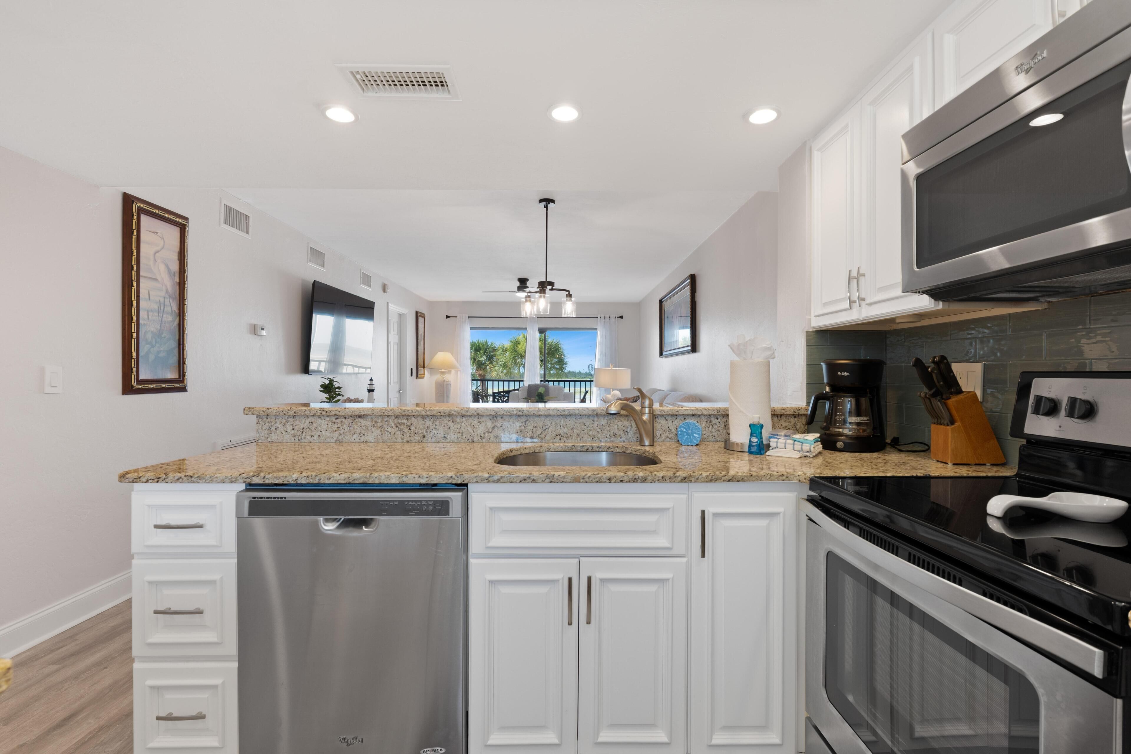 Una cocina moderna con muebles blancos, electrodomésticos de acero inoxidable y una isla central.
