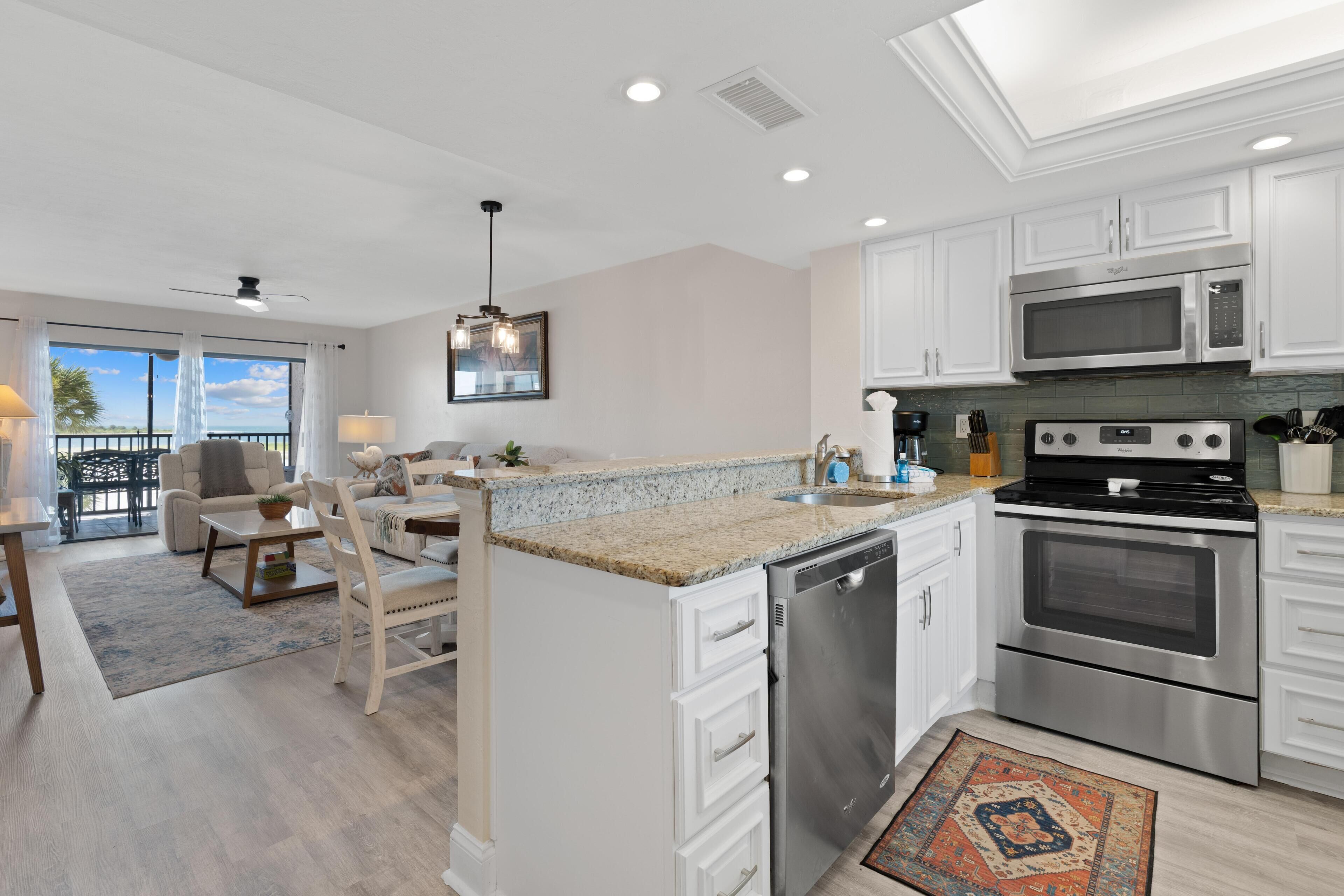 A modern kitchen with white cabinets, stainless steel appliances, and a large island.